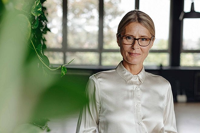 Frau mittleren Alters mit Brille schaut zielgerichtet in die Kamera.