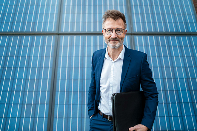 Mann im Anzug steht vor Solarpaneelen.