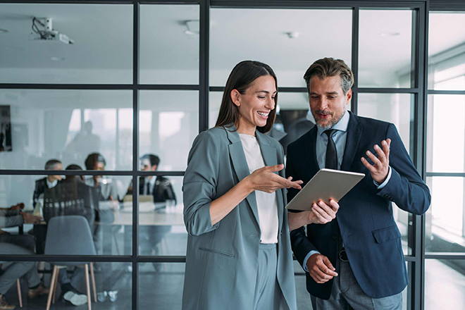 Ein Mann und eine Frau schauen lächelnd auf einen Tablet-Bildschirm.